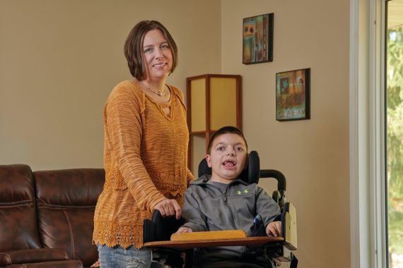 child in wheelchair and woman wearing orange shirt