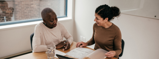 Two women sit at a table, talking.