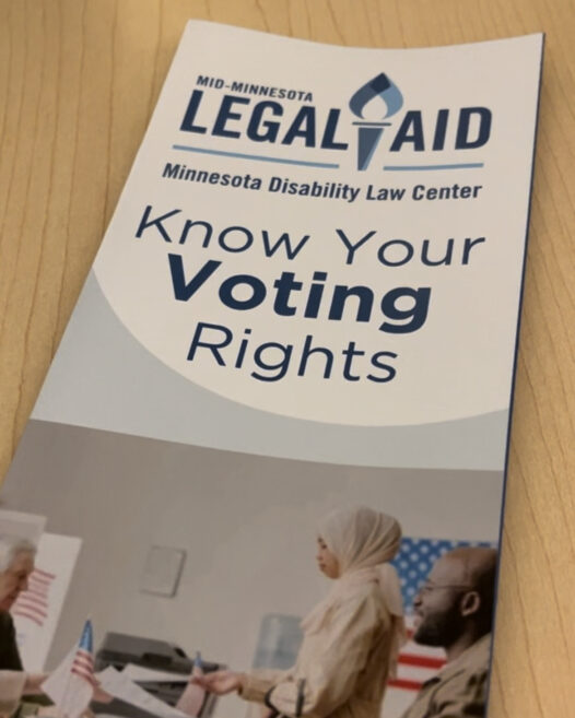 Brochure cover reads: Mid-Minnesota Legal Aid, Know Your Voting Rights. Below is image of a woman in a hijab and man in wheelchair approaching a table with election workers seated on the other side.