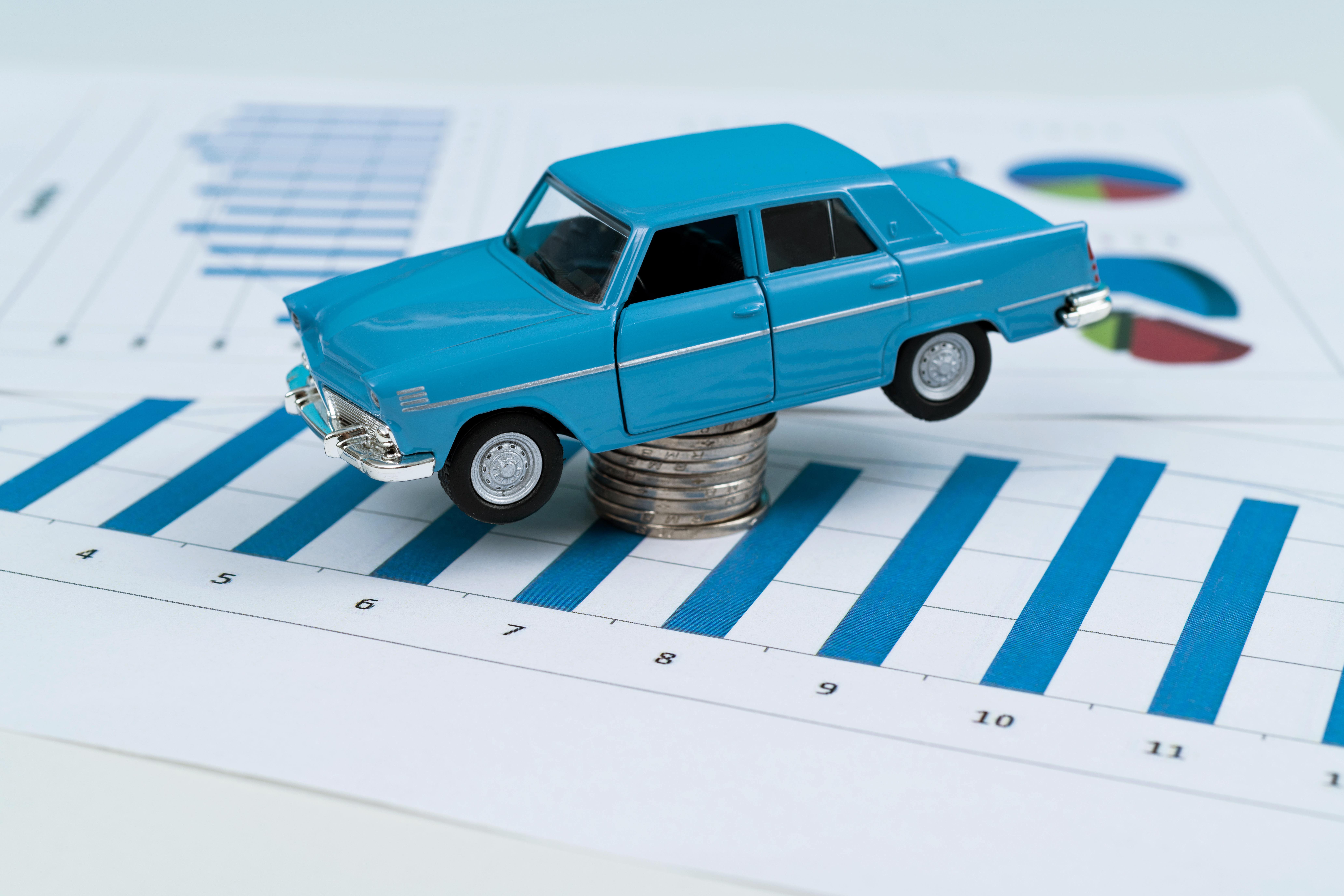 Toy car on top of stacked coins and spreadsheet