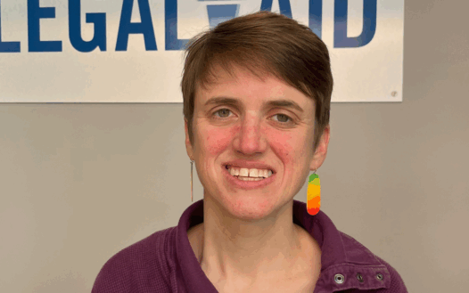 woman smiling in front of a logo for Mid-Minnesota Legal Aid