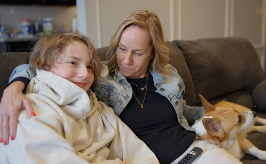 a woman and son sitting on a couch with a dog