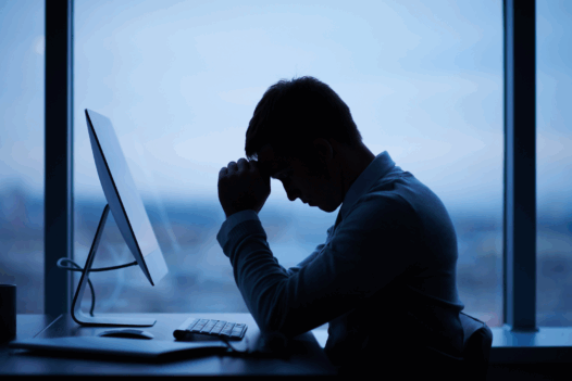 man at a desk with head in his hand