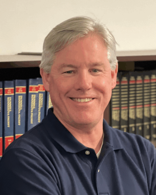 a man smiling in front of a bookshelf