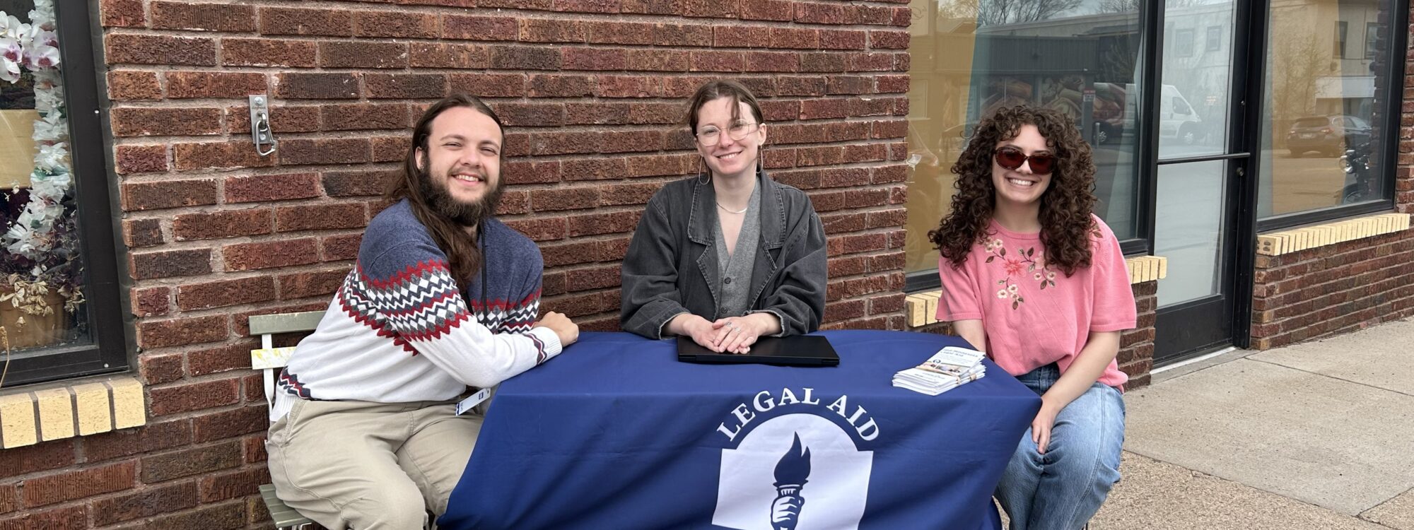 three people sitting at a table outside