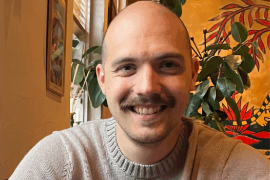 Aron smiling, sitting in a restaurant