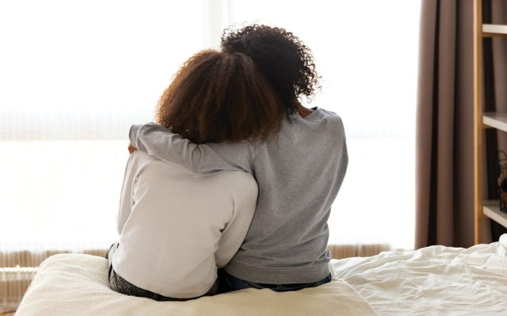 two people from behind, leaning against each other