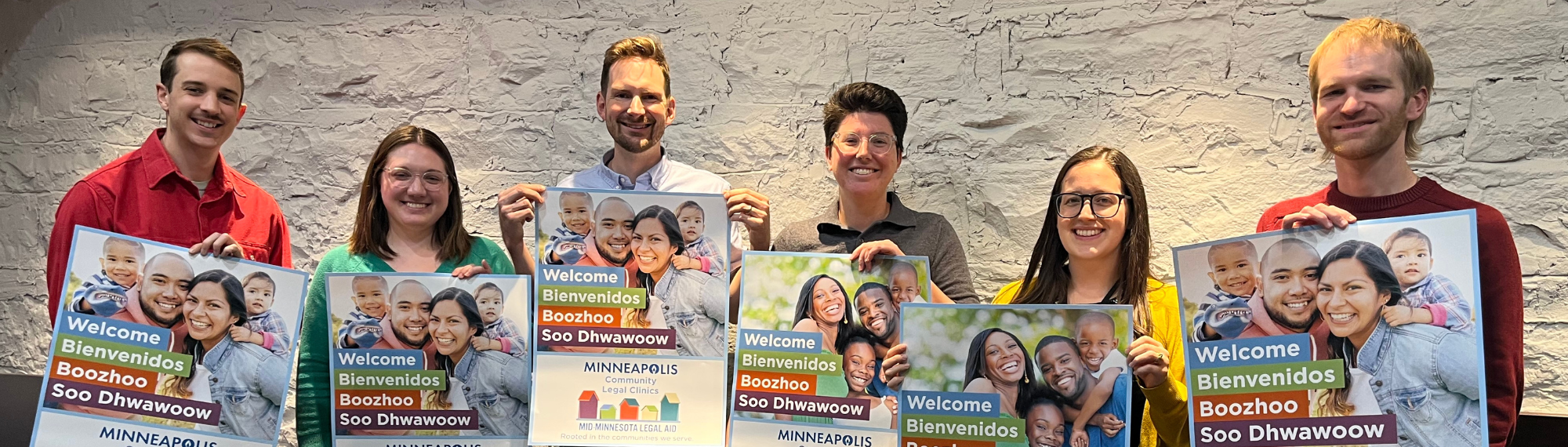 Clinic staff attorneys holding up posters promotion Minneapolis Community Legal Clinics