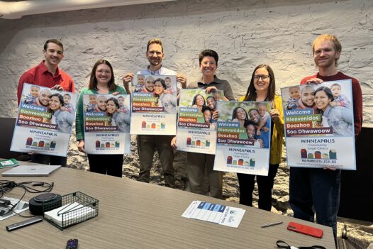 Clinic staff attorneys holding up posters promotion Minneapolis Community Legal Clinics