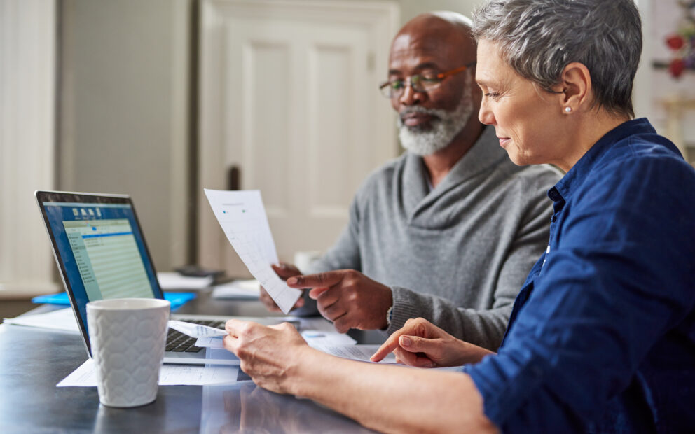 Laptop and documents with a senior couple.