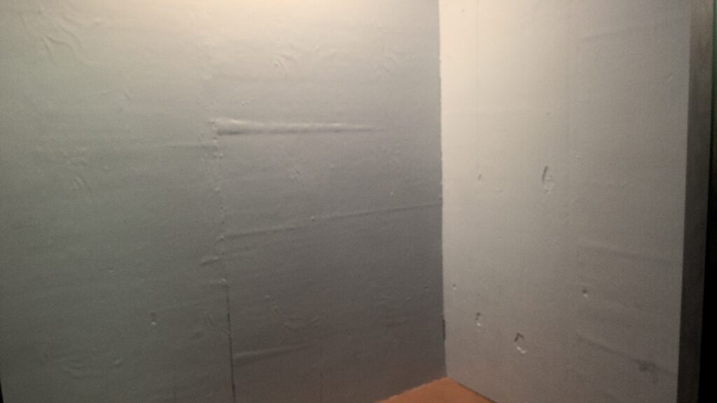 Corner joining walls. The walls are uneven plaster showing indents and dimpling.