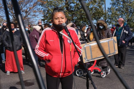 woman wearing red jacket, speaking into microphone