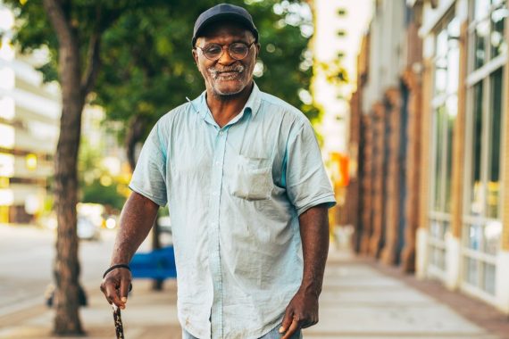 man standing on sidewalk with a cane