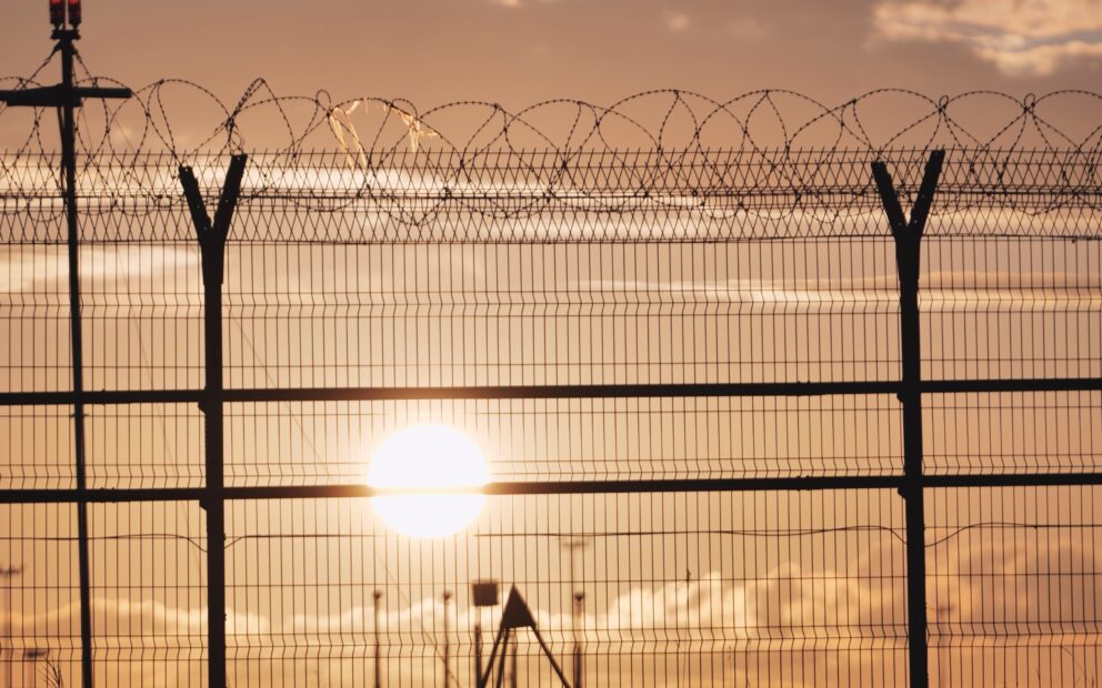 Metal fence with barbed wire during sunset