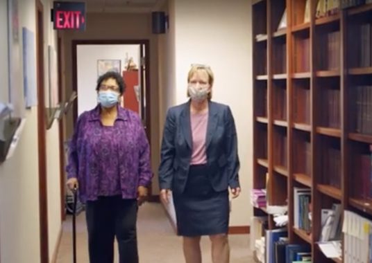 two women walking through a hallway