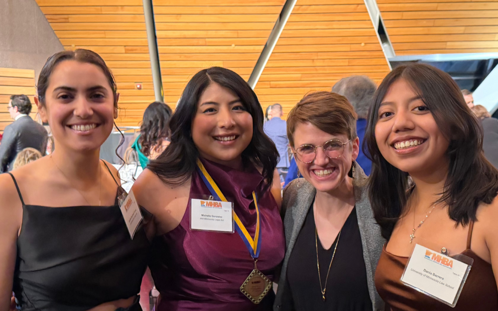 four people at a gala wearing dresses and nametags
