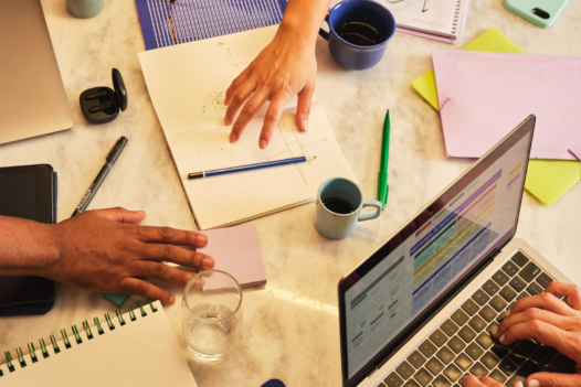 collaboration on a desk, with papers and laptops