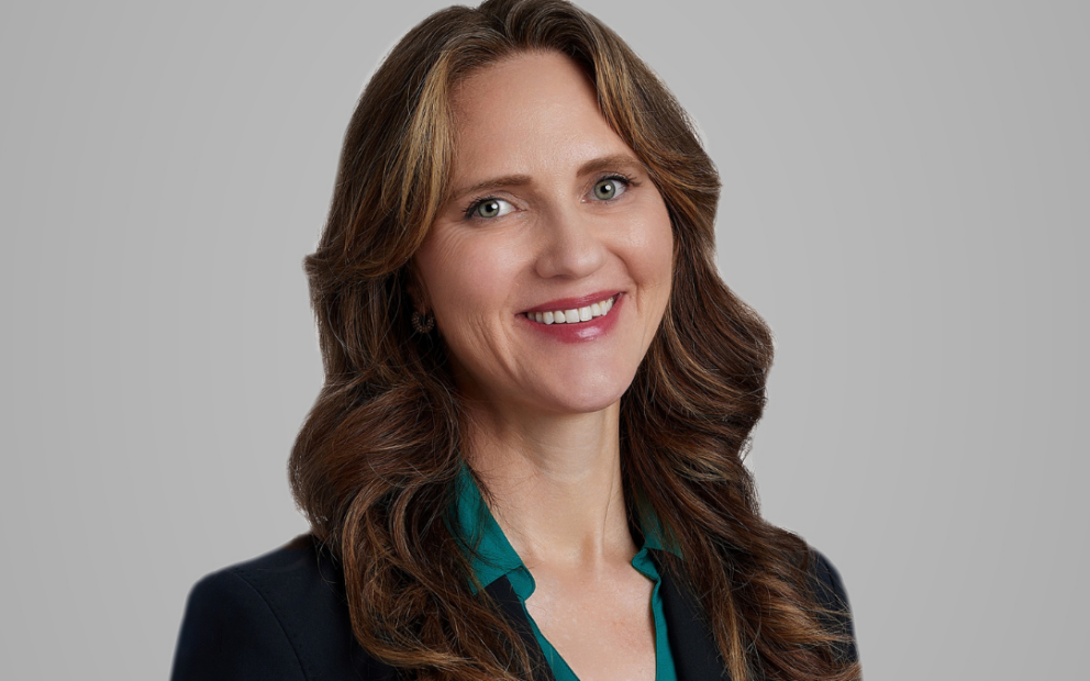 Professional photo of E. Michelle Drake, a woman with shoulder length hair brown hair wearing a black blazer over a dark green blouse.